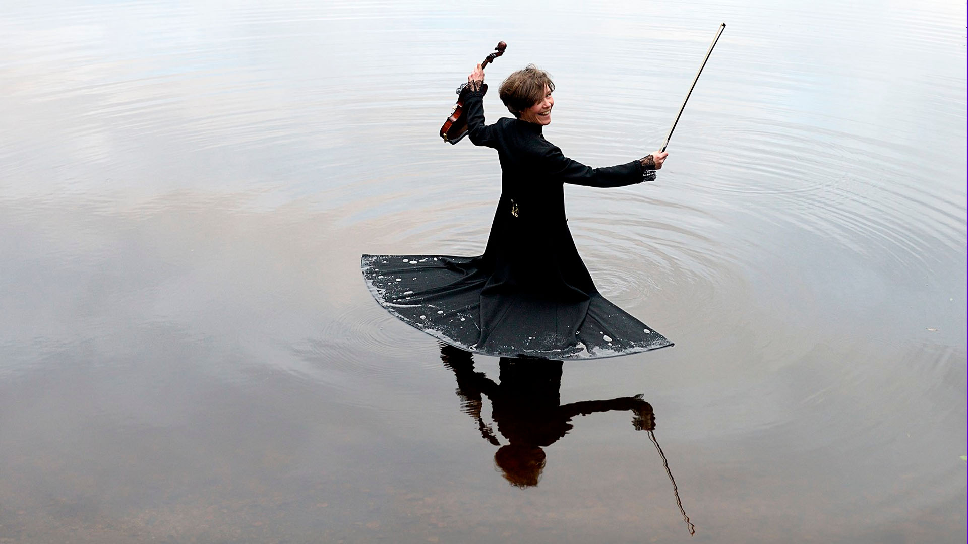 Ilmastoylikapellimestari Johanna Almark seisoo vedessä viulu kädessä.
