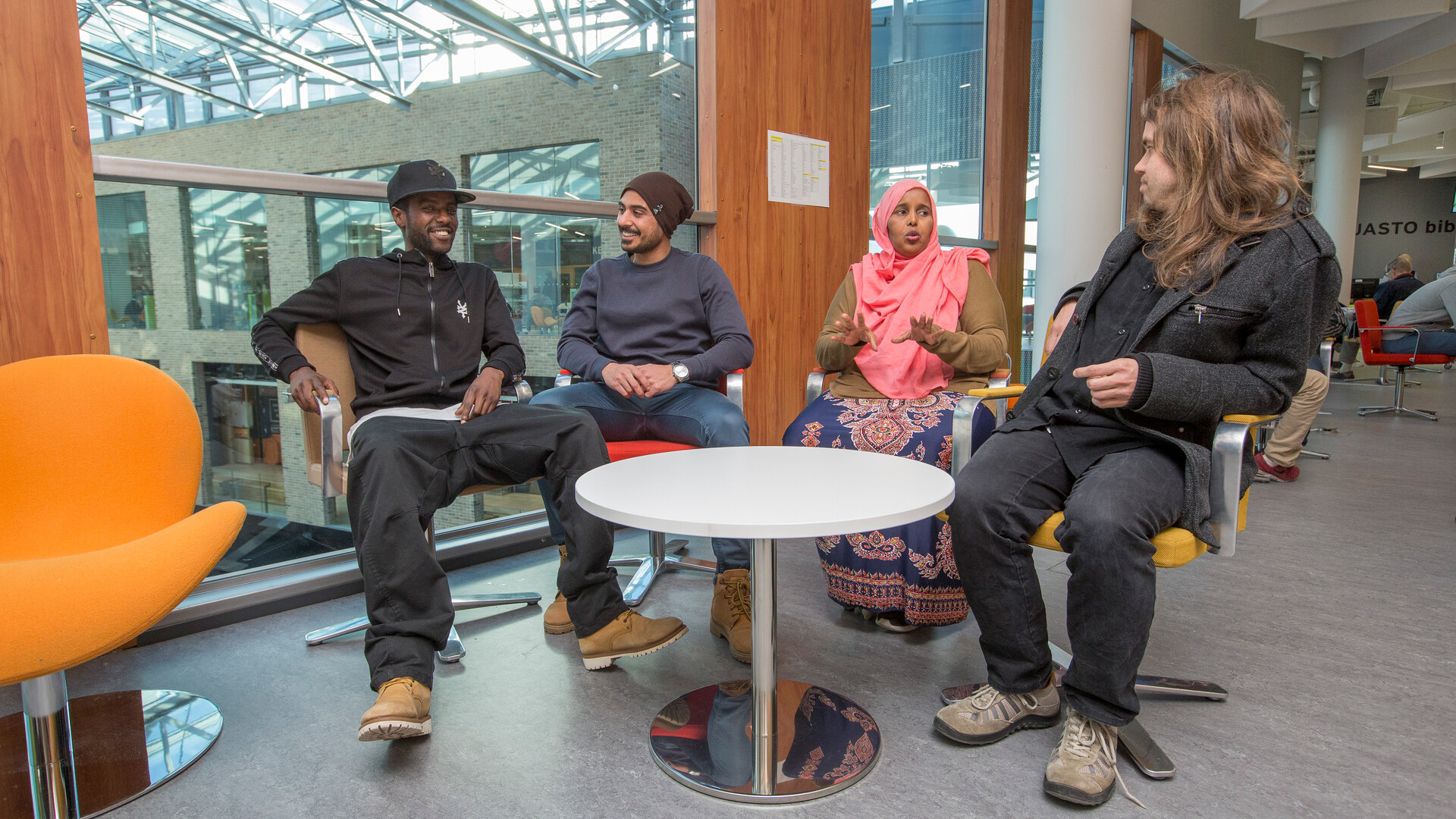 Valokuvassa neljä henkilöä keskustelee kirjastossa.