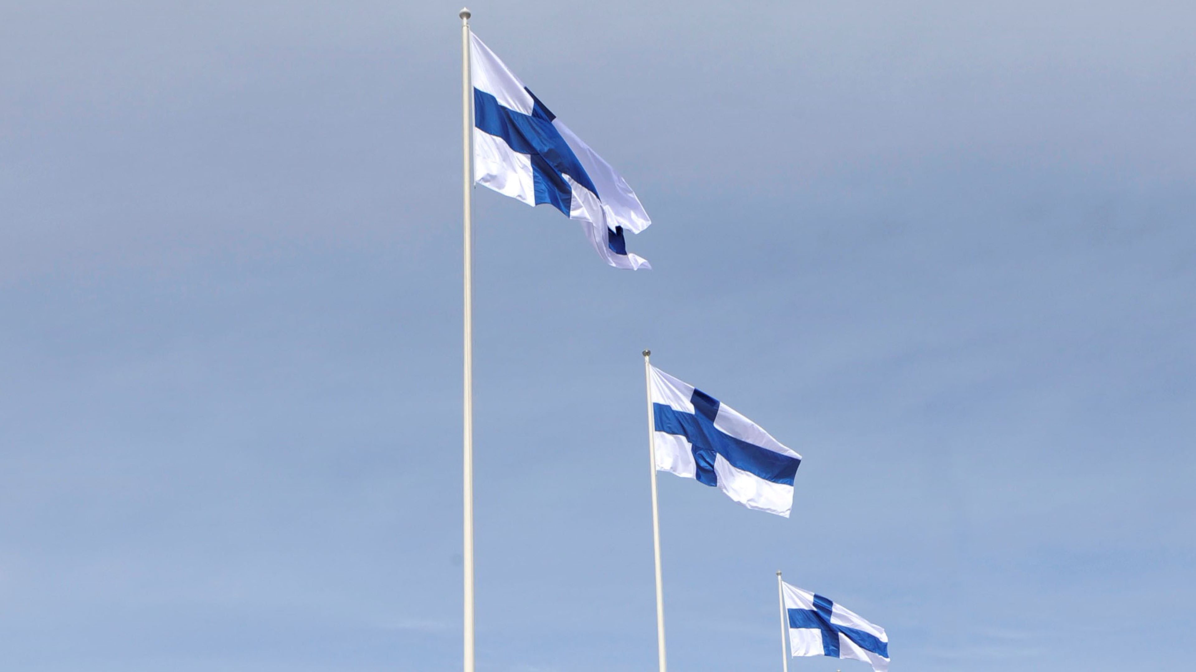 Kolme Suomen lippua liehuvat tangossa