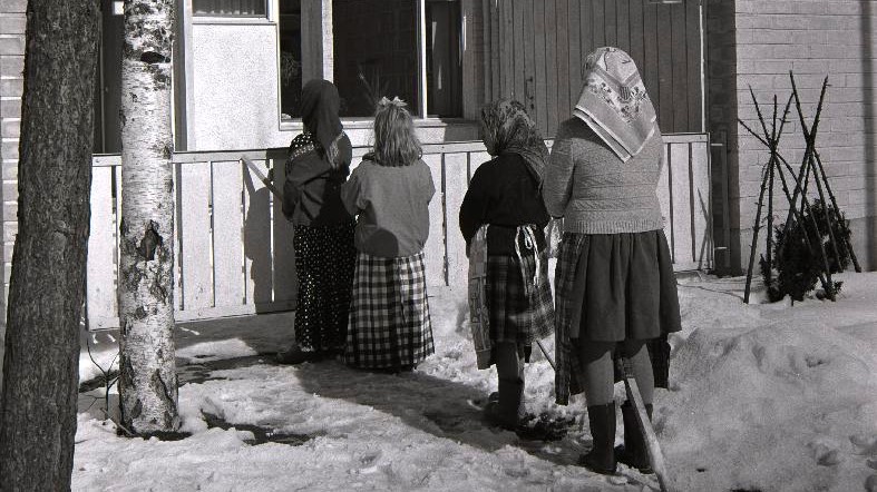 Pääsiäisnoidiksi pukeutuneet lapset seisovat talon portilla.