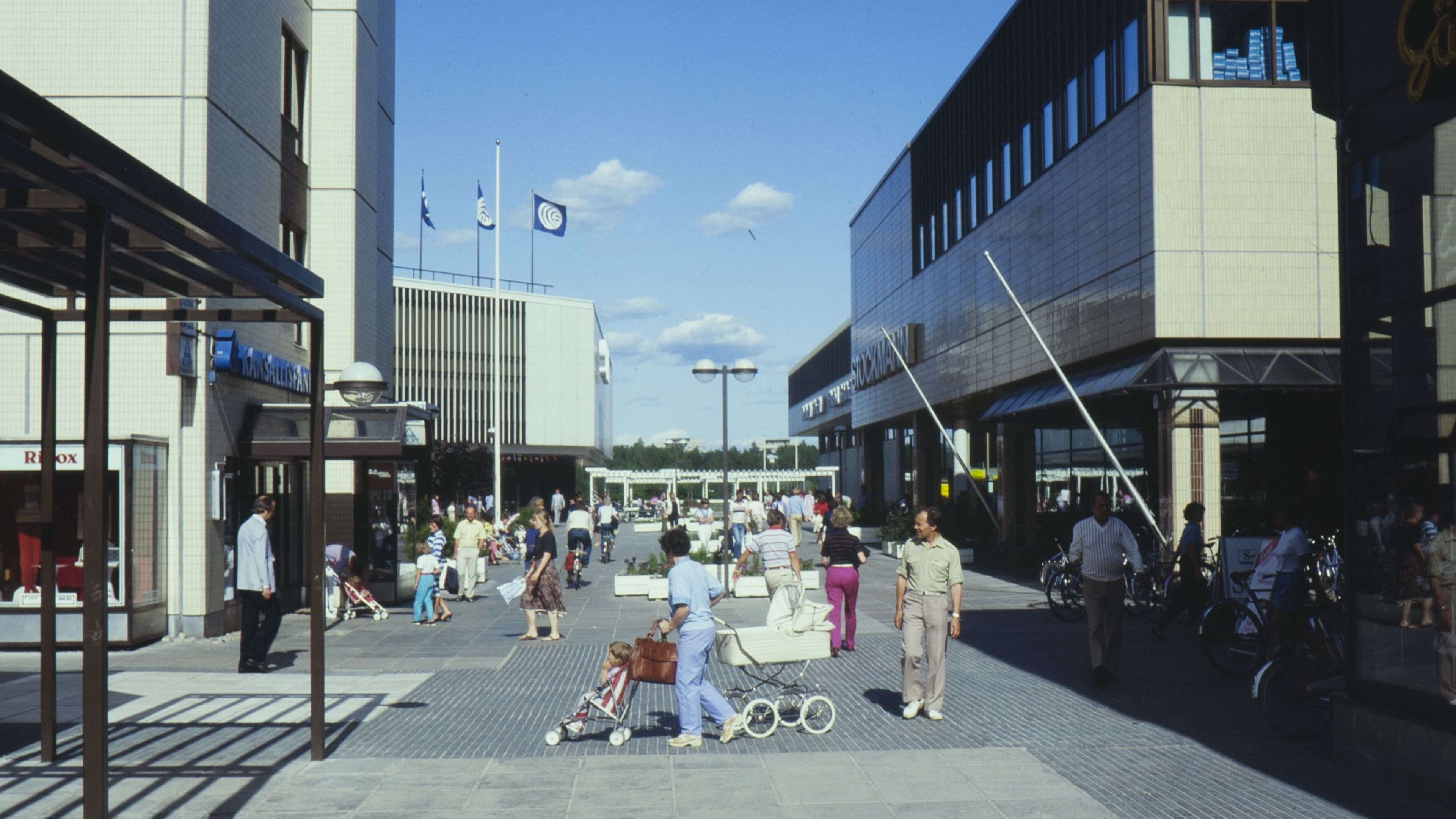 Ihmisiä lastenvaunujen kanssa Tapiolan keskustassa.
